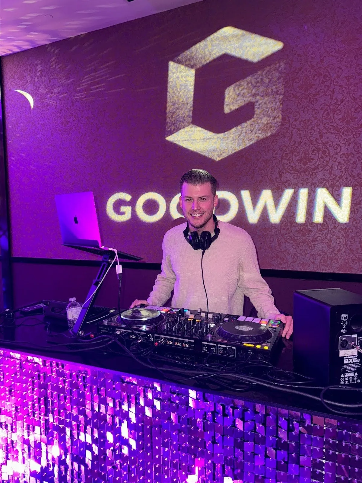 DJ MDDLCHLD performing at Goodwin corporate event with purple backdrop